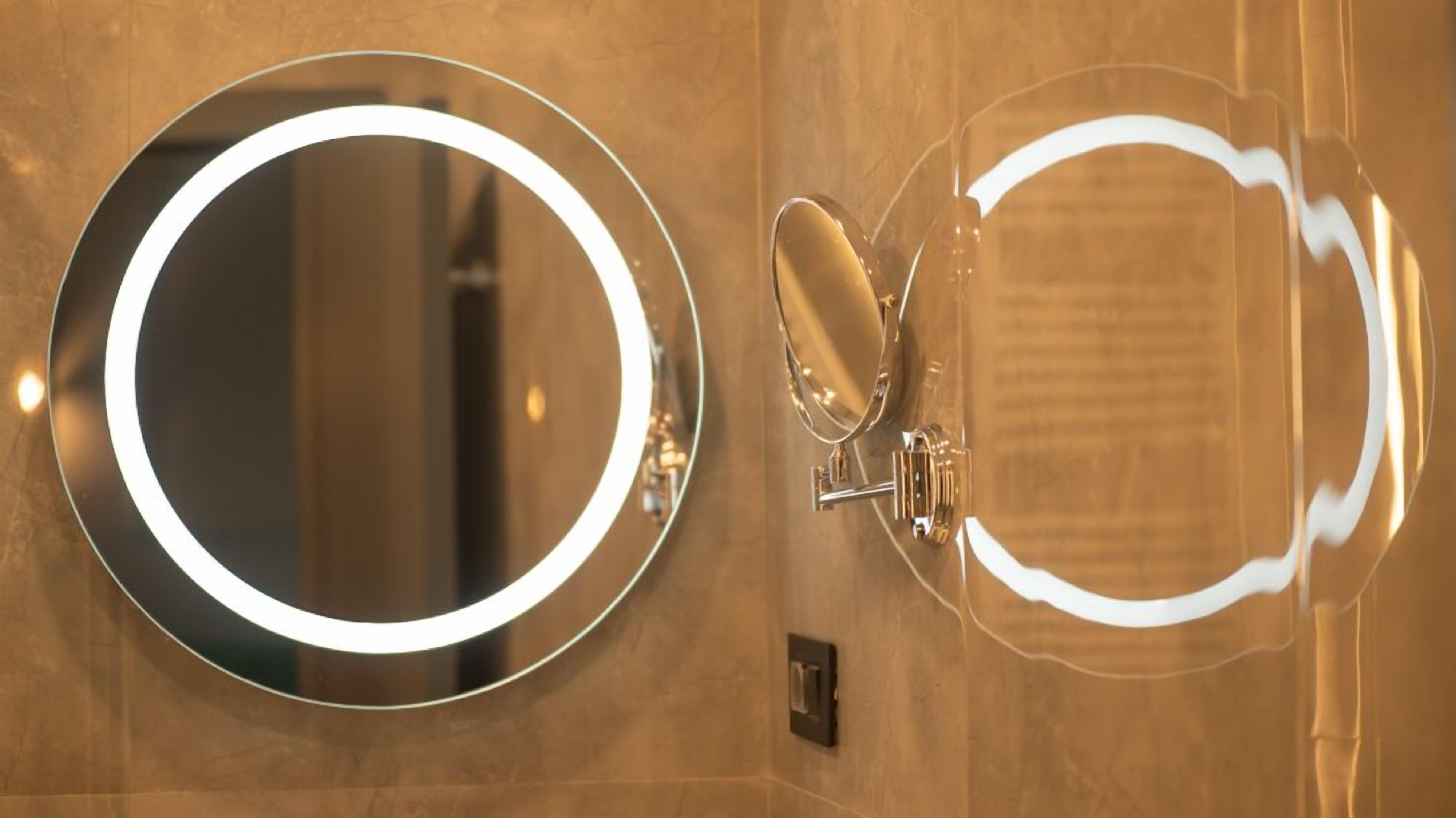 A bathroom with a round mirror and a handheld mirror.