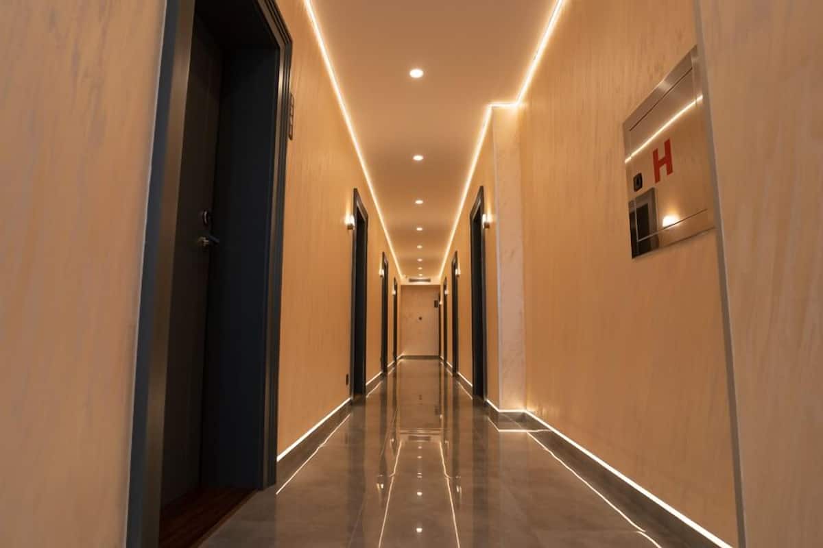 Un long couloir bien éclairé, doté d’un plancher ciré, qui mène à une porte marquée d’un « H » rouge.