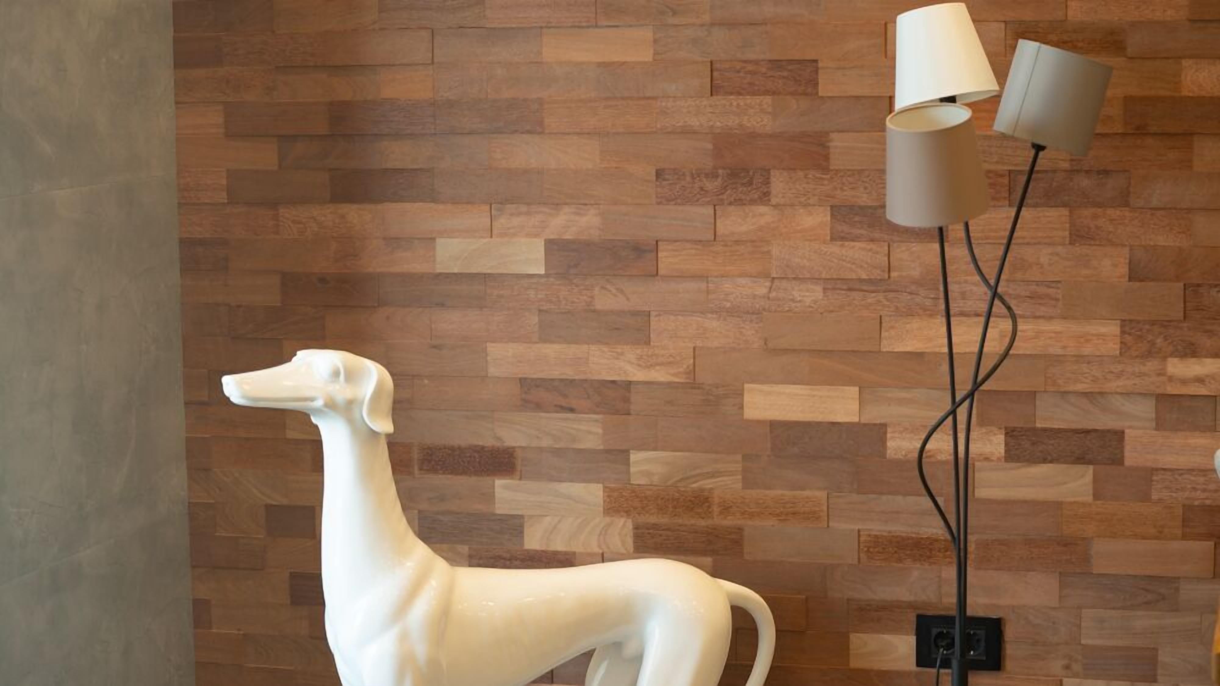 A white sculpture of a dog on a wooden wall with a modern floor lamp.