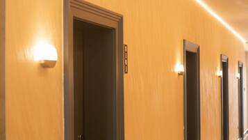A hotel hallway with doors and wall-mounted light fixtures.