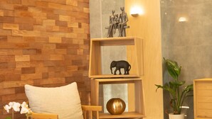 A wooden wall with a patterned design, a white chair, a shelf with decorative items, and a potted plant. - KAME HOTEL BELGRADE (Belgrade)