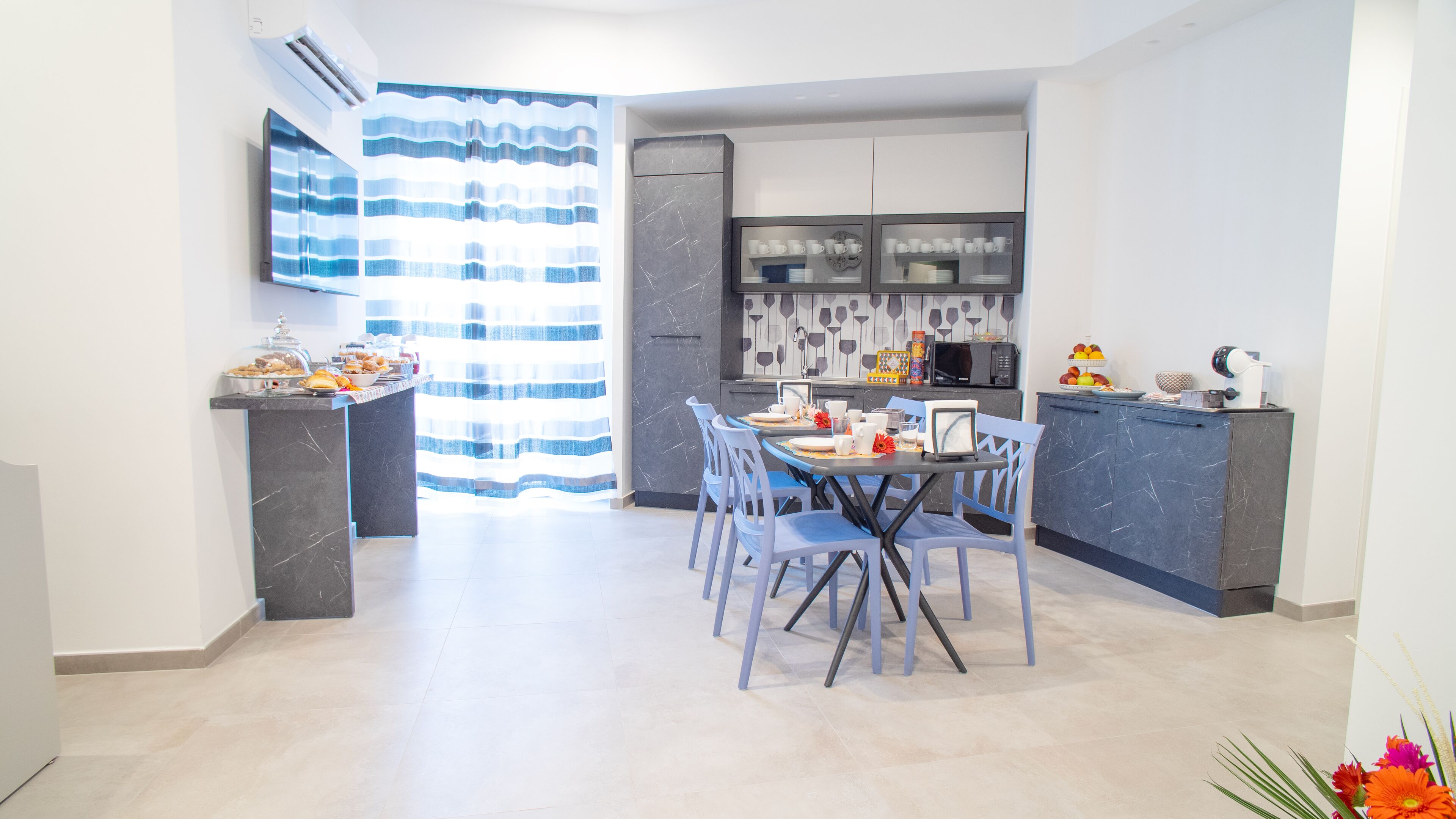 A modern kitchen with a dining area, featuring a marble countertop, a microwave, and a sink.