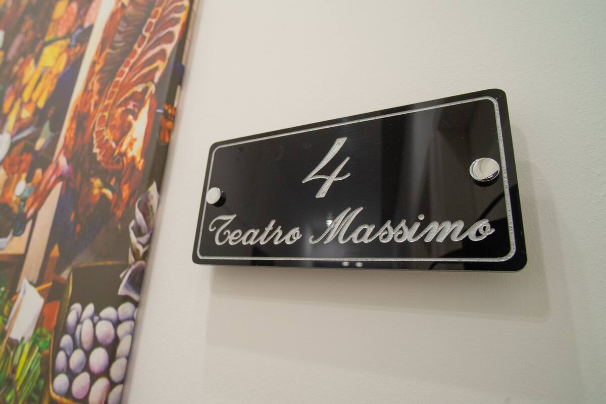 Een metalen bord met het nummer 4 en de naam 'Teatro Massimo' op een muur.
