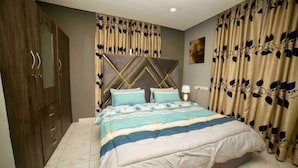A bedroom with a bed, curtains, a headboard, and a wardrobe. - 3 bedrooms | Entire Flat | Amasaman, Accra (Amasaman,)