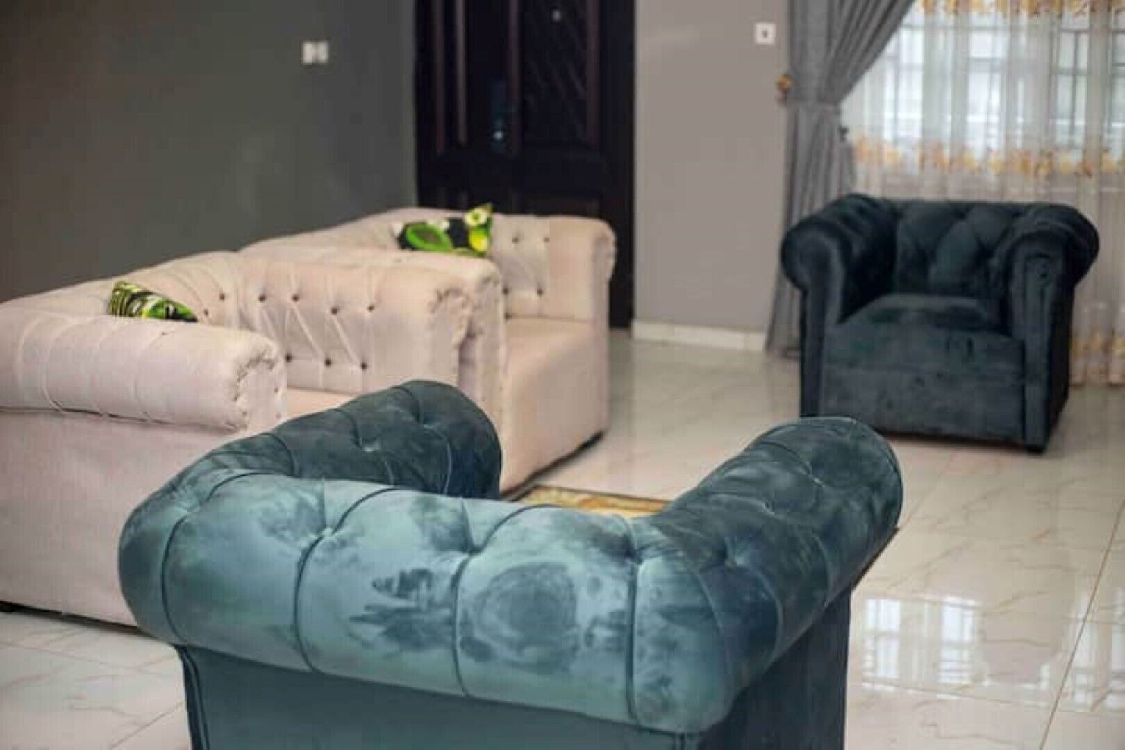 A room with three sofas, one in each corner, and a dark-colored armchair.
