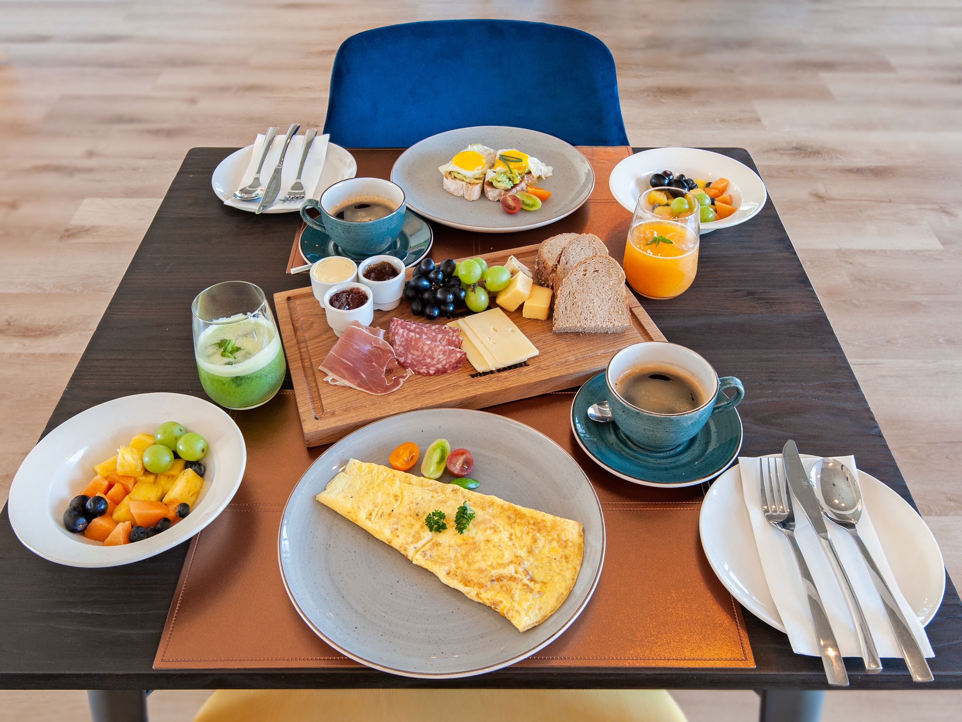 A breakfast table with plates of food, a cup of coffee, and a glass of orange juice.
