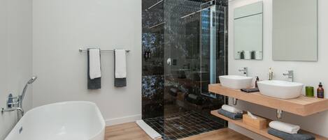 A modern bathroom with a freestanding bathtub, a glass-enclosed shower, and a vanity with two sinks.