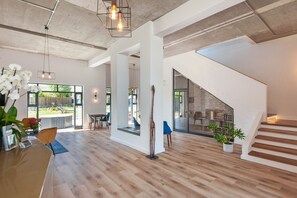 Un interior espacioso con suelo de madera, una escalera y un gran ventanal con vistas al exterior.