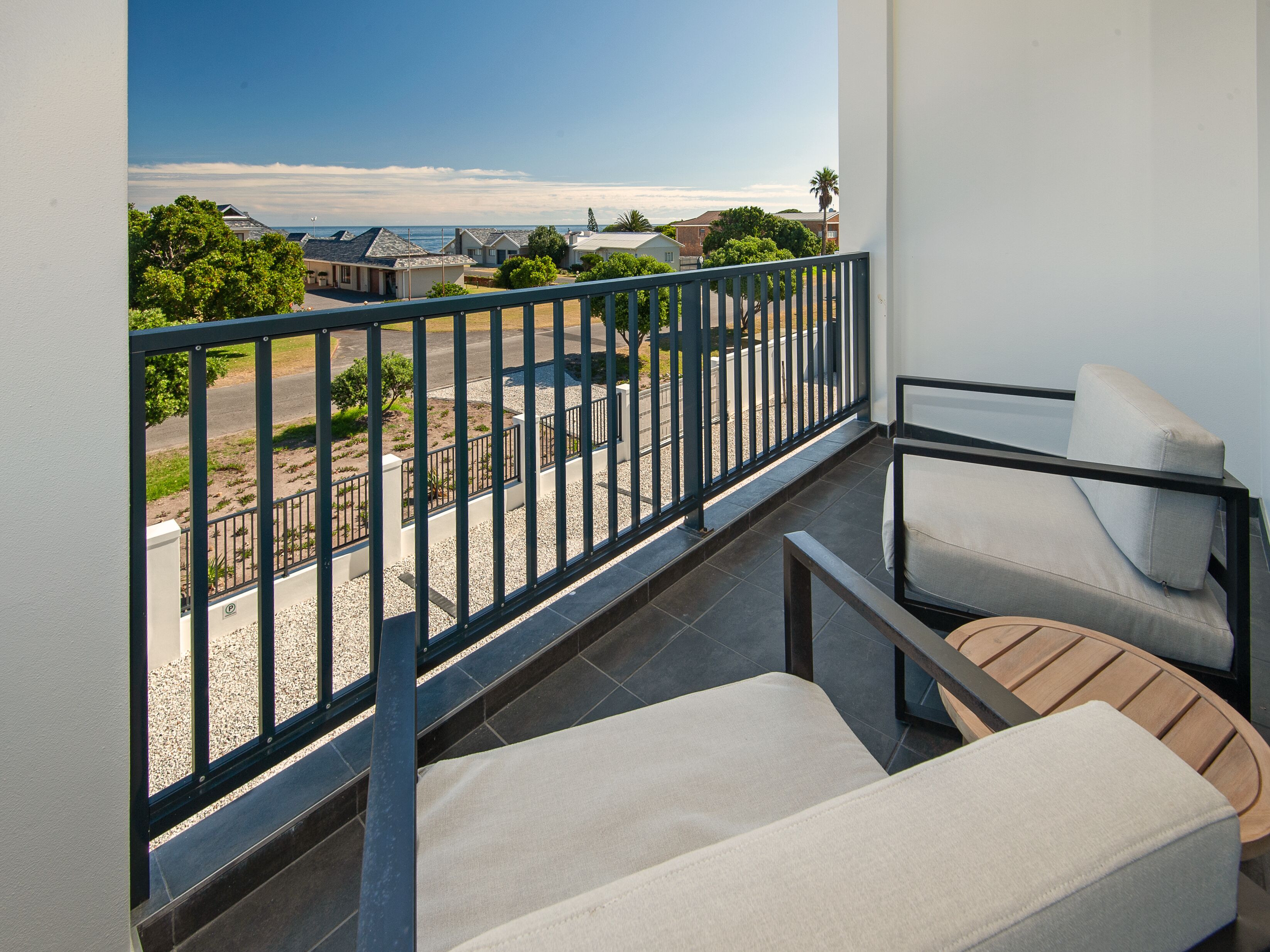 Un balcon avec vue sur la plage, un coin salon avec un canapé et une table, et une rambarde.