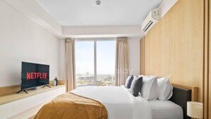 A hotel room with a bed, a TV displaying 'NETFLIX', a window with curtains, and a city view. - Karaton by Kozystay (Bandung)