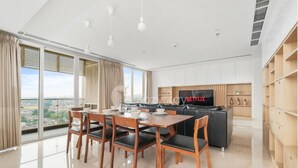 A modern living room with a dining area, a TV, and a city view. - Karaton by Kozystay (Bandung)