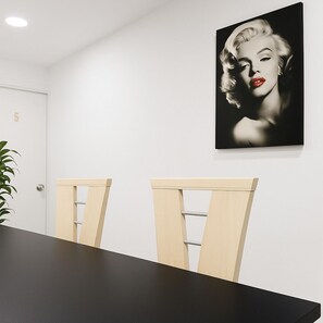 Une pièce avec une porte blanche portant le numéro 5, une table noire et deux chaises en bois.