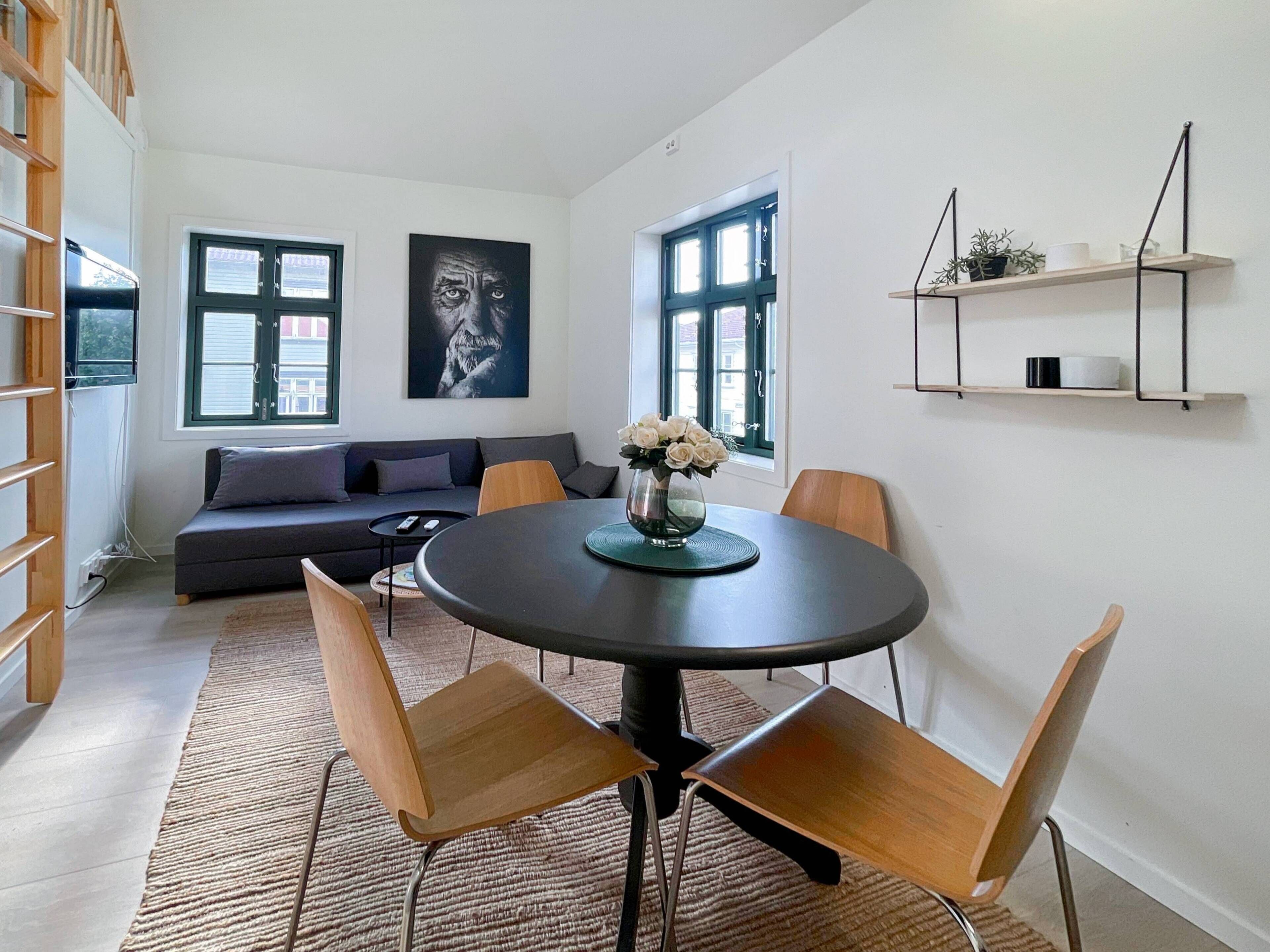 En moderne stue med et rundt bord, stole, en sofa og et maleri på væggen.