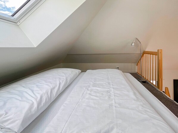 A small, single-bed room with a sloped ceiling and a skylight. - Vibrant Apartment on Bustling Street, Above a Restaurant - Perfect for Tourists, (Stavanger)