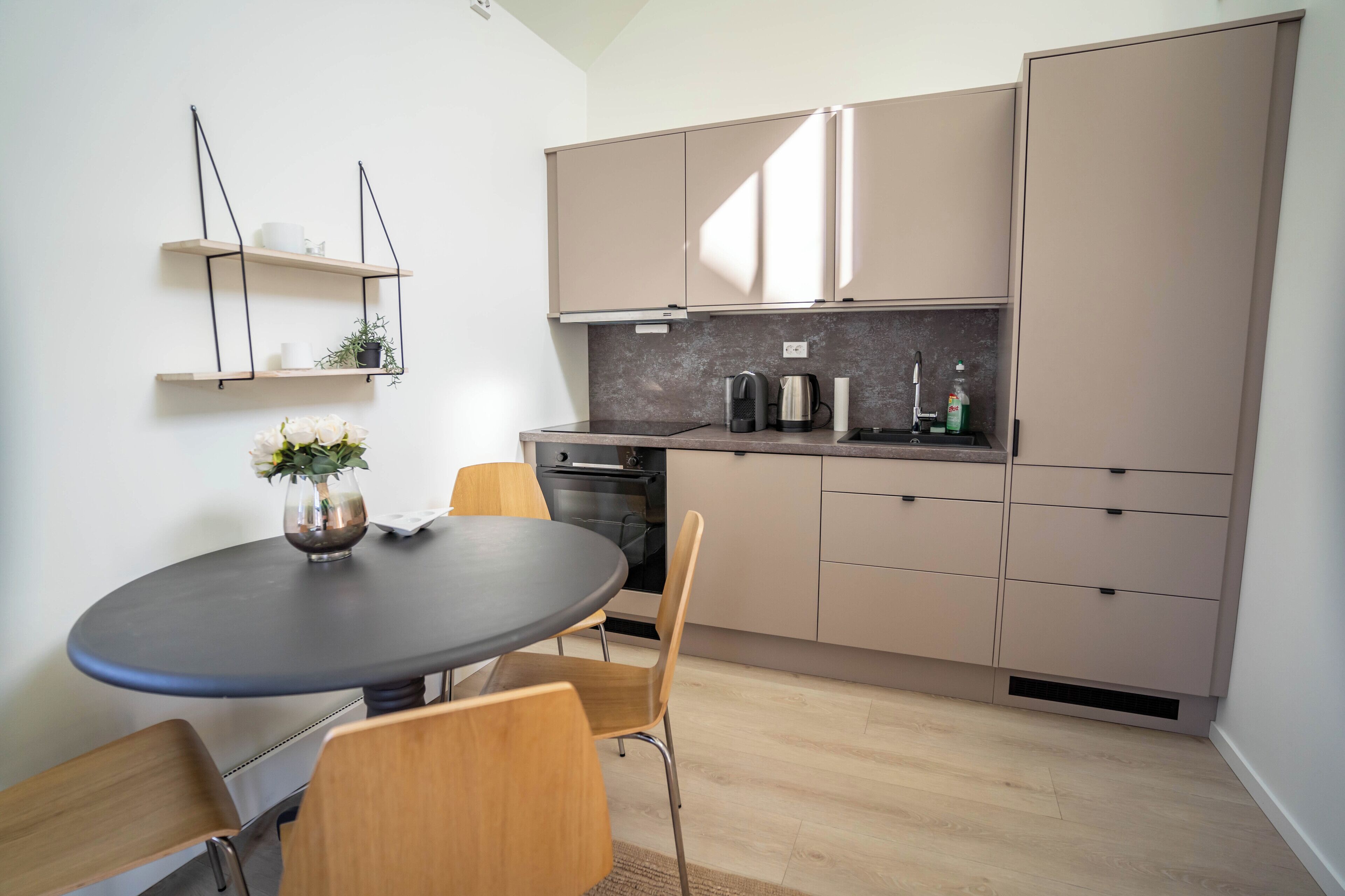 A modern kitchen with a round table, chairs, and built-in cabinets.