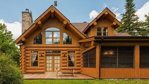 A log cabin with a large porch, multiple windows, and a chimney. - Fiddler Lake Resort - Bear 10 (Mille-Isles)