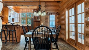 A log cabin interior with a dining area, wooden walls, and large windows. - Fiddler Lake Resort - Bear 10 (Mille-Isles)