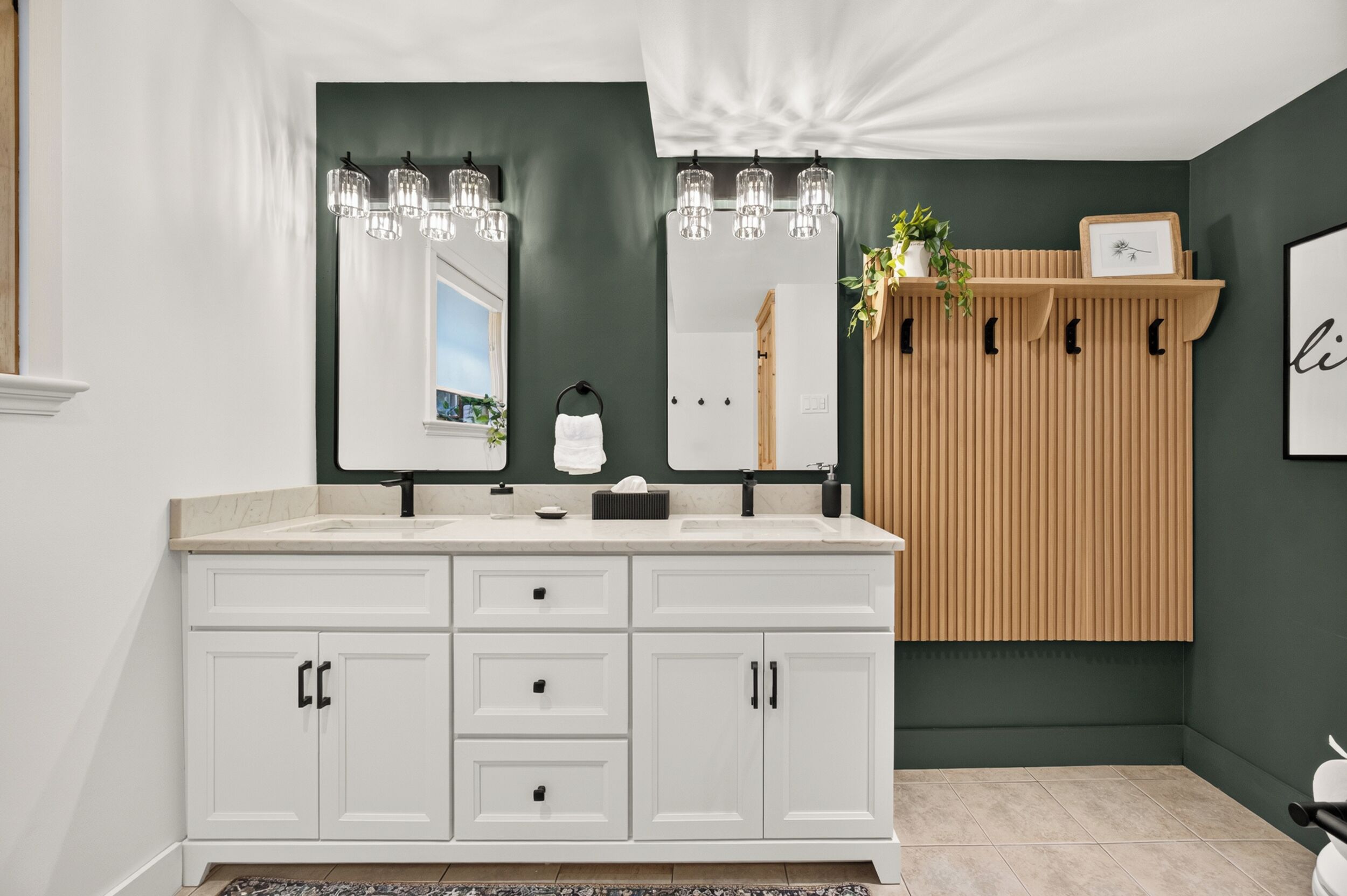 A bathroom with a white vanity, two mirrors, and a wooden panel wall.