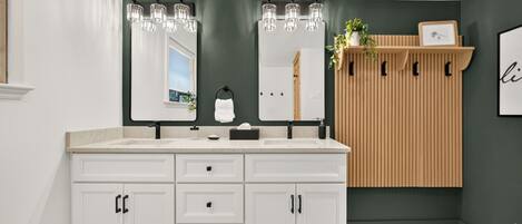 A bathroom with a white vanity, two mirrors, and a wooden panel wall.