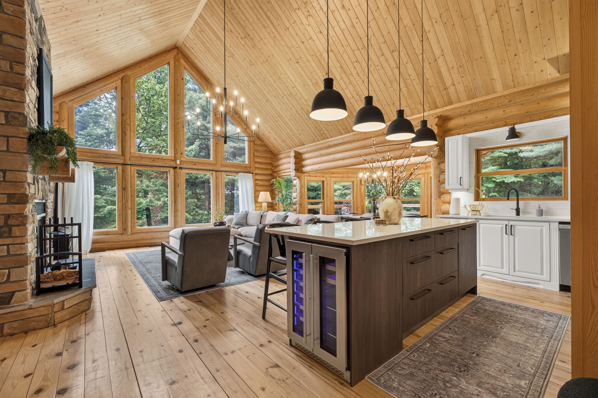 A spacious kitchen with large windows, wooden flooring, and a central island with appliances.