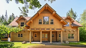 A log cabin with a symmetrical facade, a central entrance, and a porch with columns.