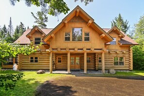 A log cabin with a symmetrical facade, a central entrance, and a porch with columns.