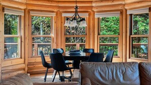A log cabin interior with a dining table, chairs, and a sofa.