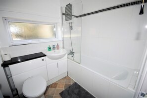 A bathroom with a toilet, sink, and shower.