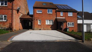 Um edifício residencial com calçada pavimentada, painéis solares no telhado e garagem.