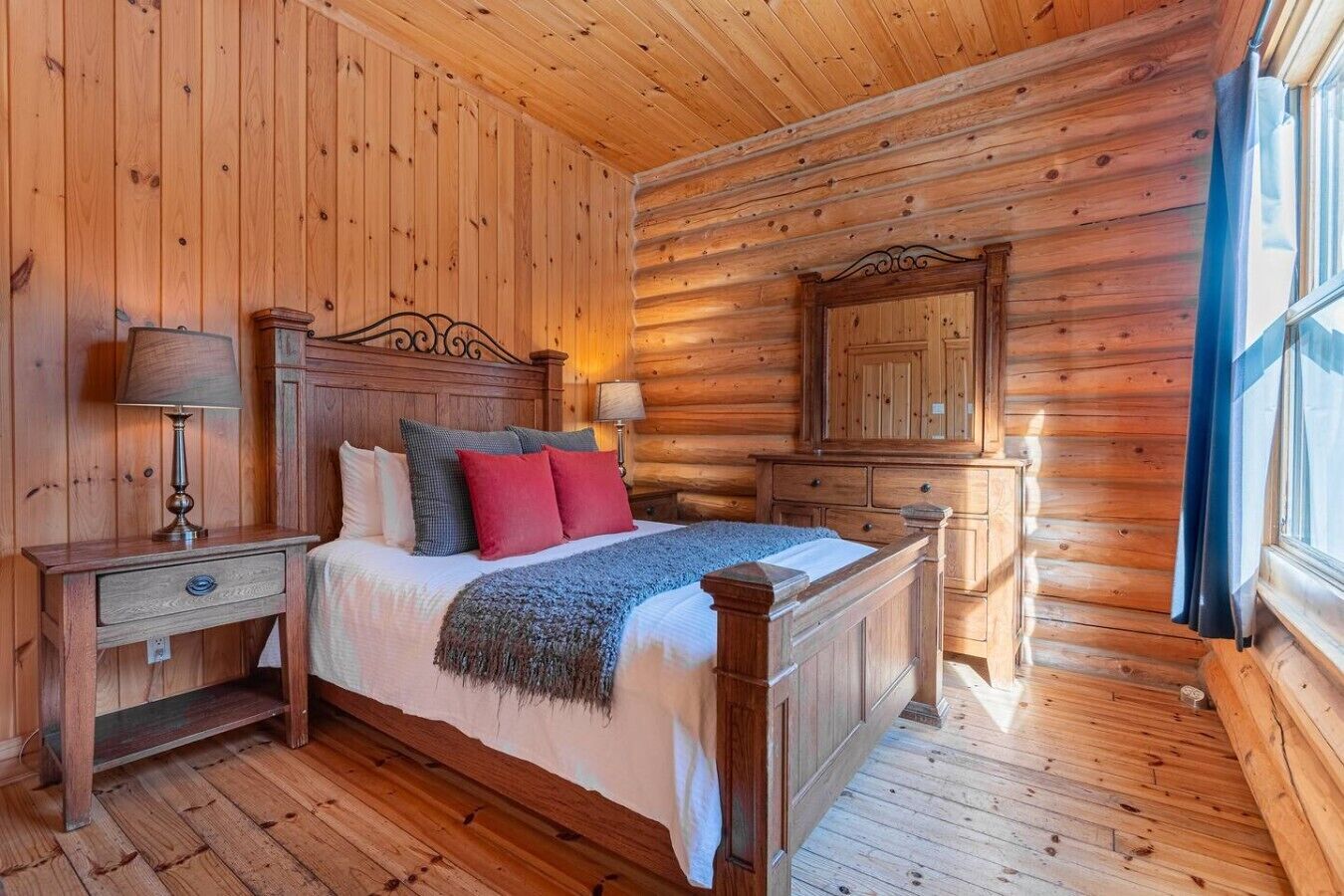 A wooden cabin bedroom with a bed, nightstands, and a mirror.