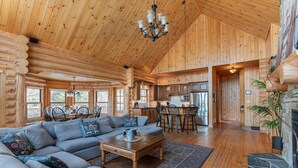 A log cabin interior with a large living room, kitchen, and dining area.