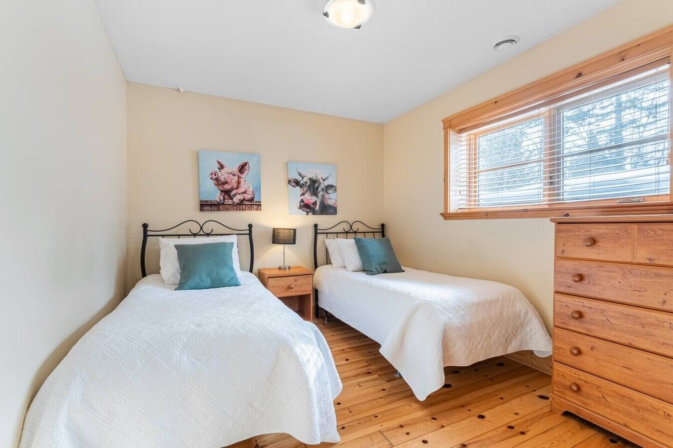 Ein Schlafzimmer mit zwei Einzelbetten, einem Holzkapständer und zwei an der Wand hängenden Bildern.