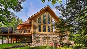 A log cabin with a stone foundation, large windows, and a deck. - Fiddler Lake Resort - Deer 30 (Mille-Isles)