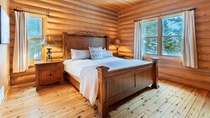 A wooden cabin bedroom with a bed, nightstands, and windows. - Fiddler Lake Resort - Deer 30 (Mille-Isles)