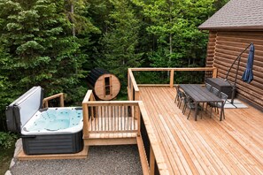 A wooden deck with a hot tub, a sauna, and a dining area with outdoor furniture. - Fiddler Lake Resort - Rabbit 57 (Mille-Isles)
