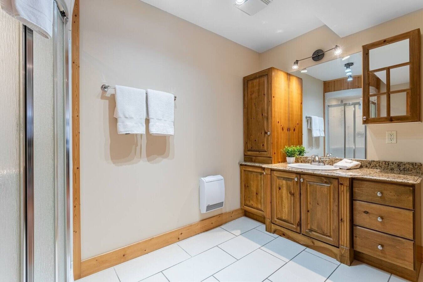 Un bagno con mobili in legno, un lavandino, uno specchio e due asciugamani appesi al muro.