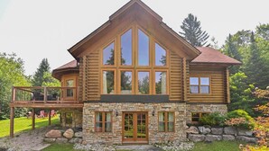 A log cabin with a stone foundation, large windows, and a deck. - Fiddler Lake Resort - Deer 86 (Mille-Isles)