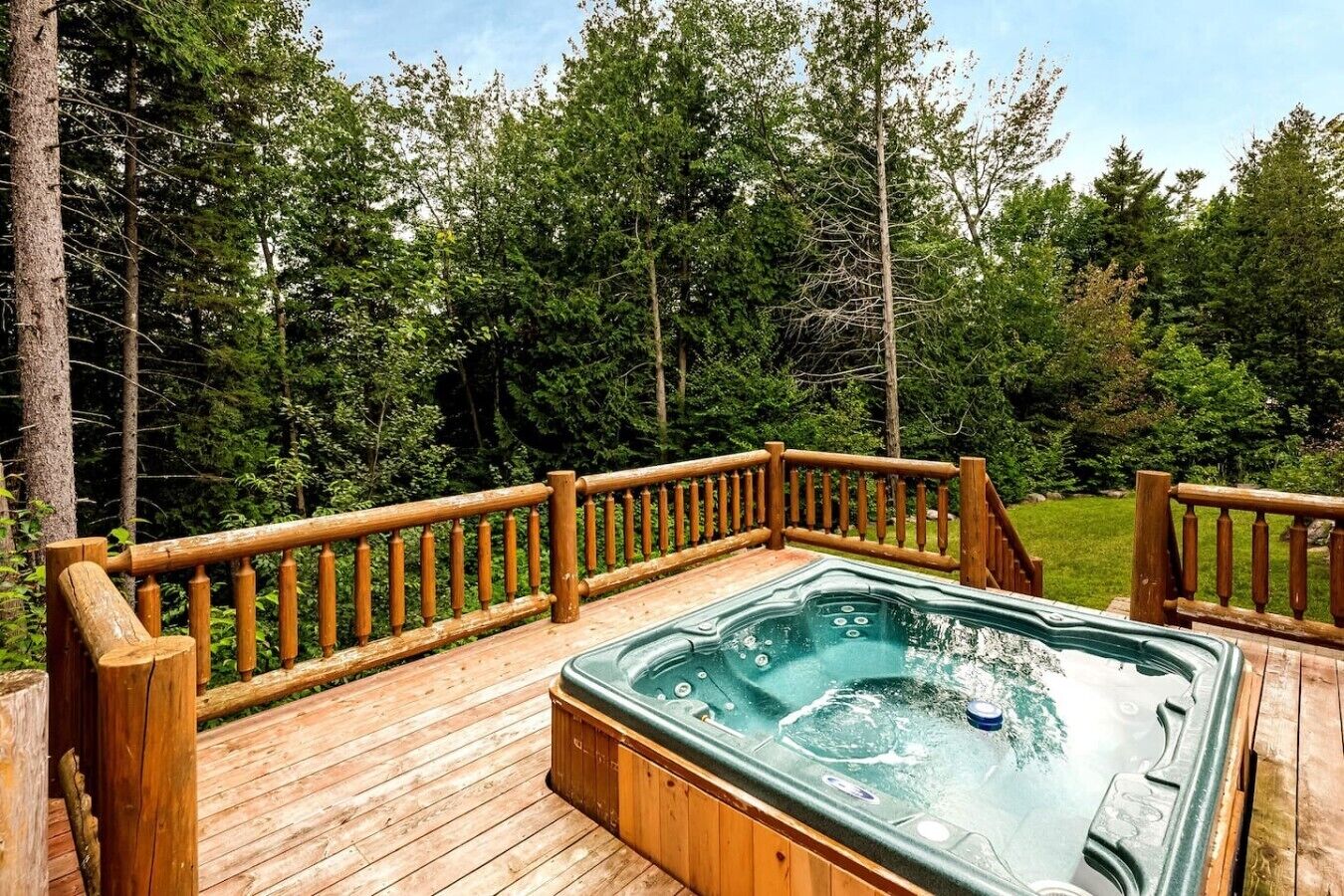 A hot tub on a wooden deck surrounded by trees.
