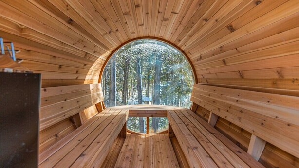 Eine runde Holzkonstruktion mit Bänken und Blick auf einen Wald.