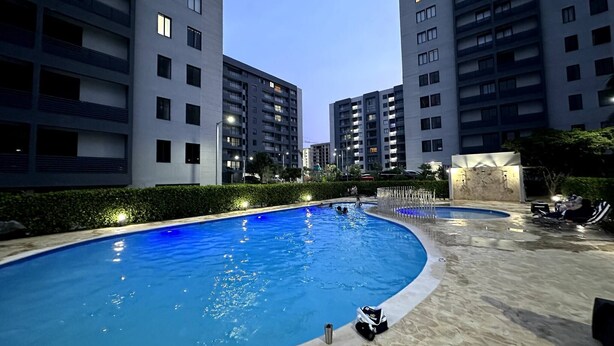 A swimming pool with a curved edge, surrounded by a stone deck. - Premium Space In Santiago- 5 Min Away From Airport (Puñal)
