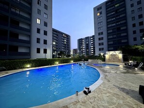 A swimming pool with a curved edge, surrounded by a stone deck.