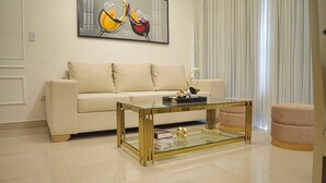 A living room with a beige sofa, a glass coffee table with gold accents, and a painting of wine glasses on the wall. - Premium Space In Santiago- 5 Min Away From Airport (Puñal)