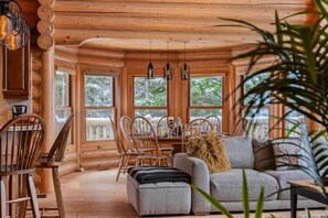 L’intérieur d’une cabane en rondins comprend un coin repas, des sièges et de grandes fenêtres.