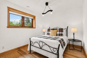 A bedroom with a bed, two bedside tables, a window, and a ceiling light fixture.