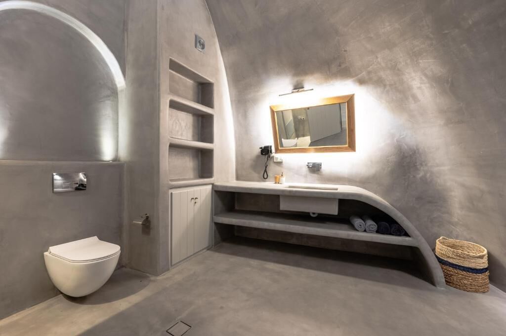 Un baño moderno con inodoro integrado, tocador con espejo y repisa con artículos de aseo.