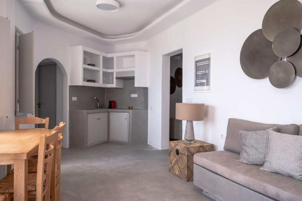A modern living room with a sofa, a dining table, and a kitchen area with cabinets and a countertop.