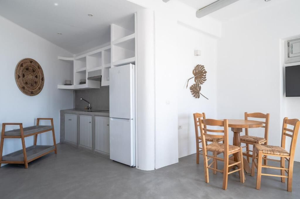 A modern kitchen with white cabinets, a built-in refrigerator, and a dining area with wooden chairs and a table.