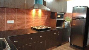Une cuisine avec un mur de fond en briques, une cuisinière à gaz, un réfrigérateur en acier inoxydable et des armoires en bois.