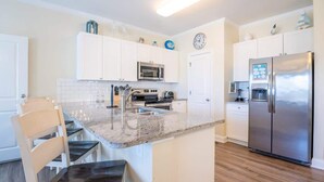 Eine moderne Küche mit weißen Schränken, einem Edelstahl-Kühlschrank, einer Mikrowelle und einem eingebauten Backofen.