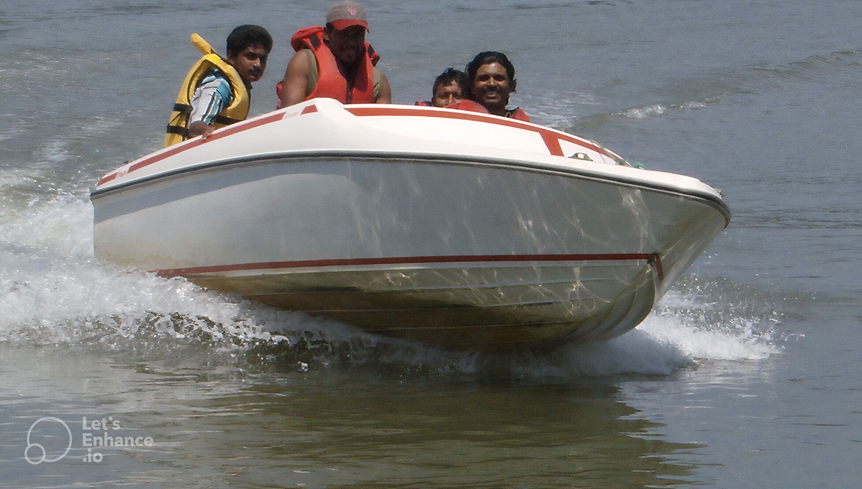 A speedboat with passengers wearing life jackets.